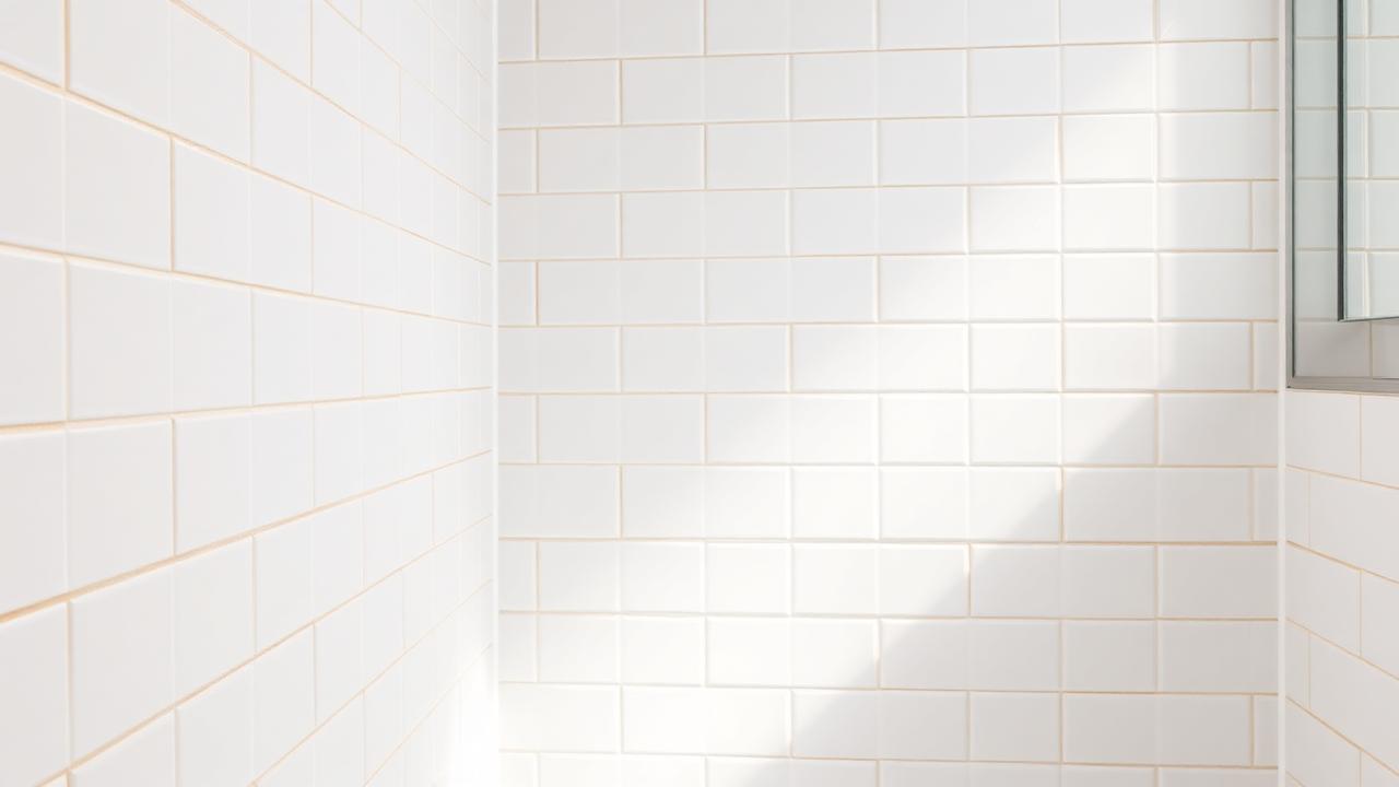 Badezimmer mit verfärbten Fugen zwischen weißen Fliesen
